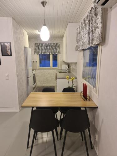 een keuken met een houten tafel en zwarte stoelen bij Home nest in Seinäjoki