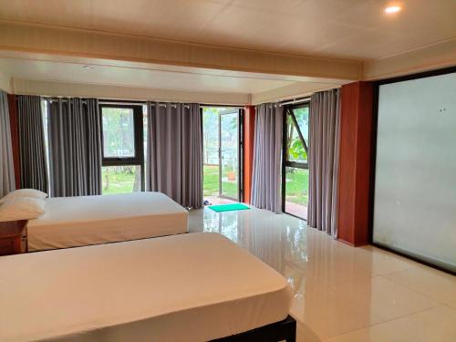 a bedroom with two beds and a large window at Carambola Bungalow in Phong Nha