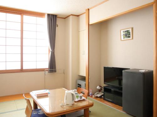 een woonkamer met een tafel en een televisie bij ピンネシリ温泉望岳荘 