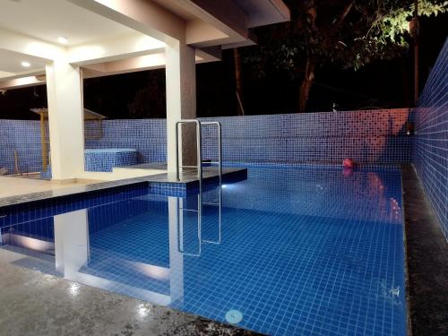 a swimming pool with blue tiles on the side of a house at C V Inn in Baga