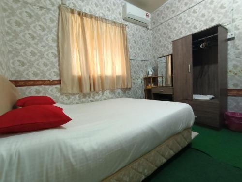 a bedroom with a bed with two red pillows on it at Mountain View Guest House KB in Kota Belud