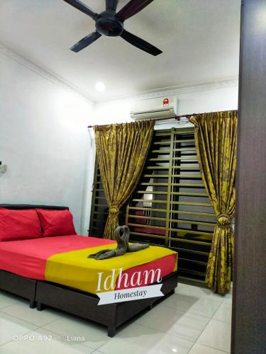 Idham homestay في ايبوه: غرفة نوم بسرير اصفر واحمر ومروحة سقف