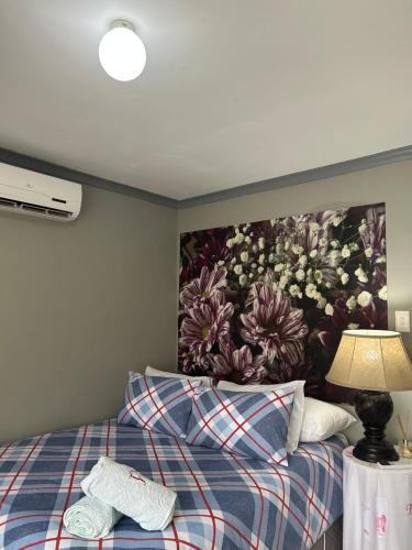 1 dormitorio con 1 cama con una pintura en la pared en Jobe Guesthouse, en Pietermaritzburg