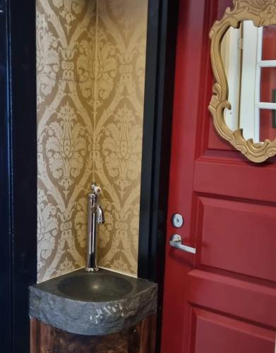 a bathroom with a sink next to a red door at Wanha Neuvola Guesthouse in Pieksämäki