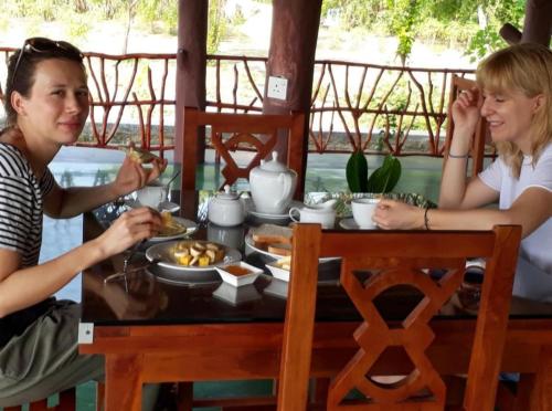 two women sitting at a table eating food at Pearl Cave Cabanas & Resturant in Tangalle