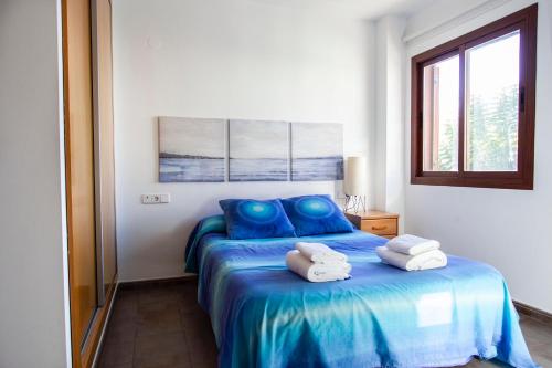 a bedroom with a blue bed with towels on it at Apartamento a 50 metros de la playa, Luminoso y acogedor in Oliva