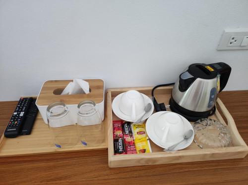 dwa drewniane tace z talerzami i czajnik do herbaty na stole w obiekcie PP. Valentine Bungalow w Ko Phi Phi