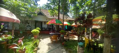 un patio con mesas y sombrillas frente a una casa en Marari Nadiya, en Mararikulam