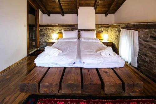 ein Bett mit weißer Bettwäsche und Kissen auf einem Holzboden in der Unterkunft Yancheva Guest House in Delchevo