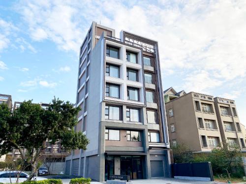 Un alto edificio bianco con un albero davanti di alfar Hotel a Dayuan