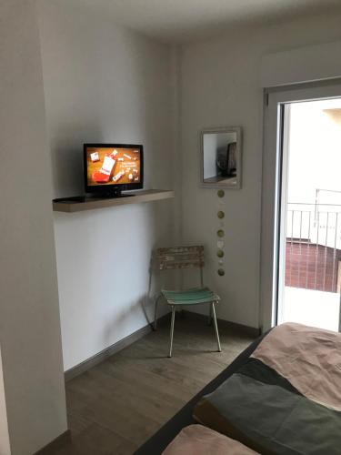 ein Schlafzimmer mit einem TV an der Wand mit einem Stuhl in der Unterkunft Villa Rita in Grado