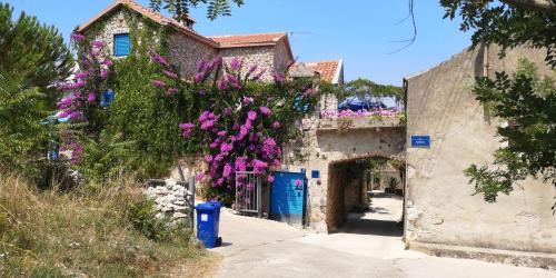 an alley with purple flowers hanging from a building at Charming dalmatian apartment with panoramic view in Tkon