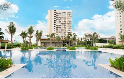 einem großen Pool mit Palmen und einem hohen Gebäude in der Unterkunft Alabang Condominium PHC in Manila