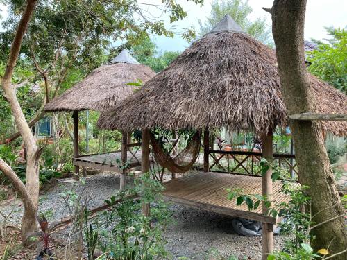 two huts and a wooden bench in a forest at Sanssouci Kep in Kep