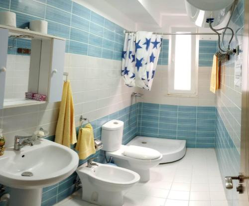 a blue tiled bathroom with a toilet and a sink at Comfortable apartment in Shëngjin