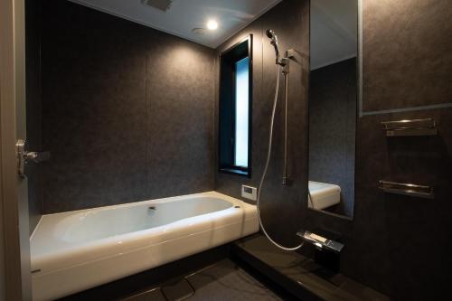 ein Bad mit einer Badewanne und einem Fenster in der Unterkunft Awaji-shima C-Side Dual View - Vacation STAY 88182v in Minamiawaji
