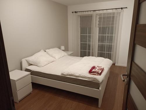 a small bedroom with a white bed with a window at Apartament Krucze Łąki in Kruklanki