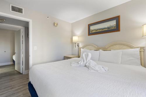 a bedroom with a white bed with a bow on it at Oceanfront Condo in Atlantica Resort near Boardwalk in Myrtle Beach