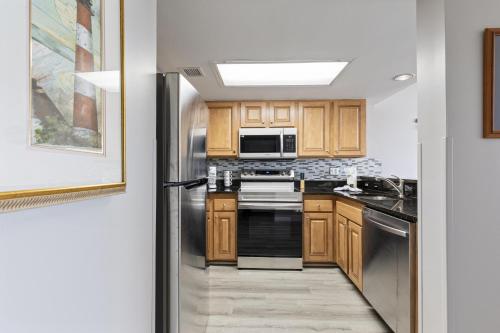 a kitchen with wooden cabinets and a stainless steel refrigerator at Oceanfront Condo in Atlantica Resort near Boardwalk in Myrtle Beach