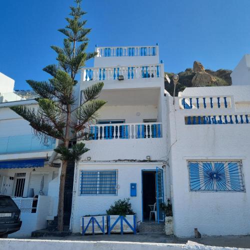 a white house with a palm tree in front of it at Rychance Playa Blanca Tanger in Tangier