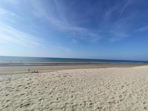 a beach with people sitting on the sand and the ocean at La Baie L’Etoile, Apt 4 pers, bord de mer, parking privé, Fort Mahon Plage in Fort-Mahon-Plage