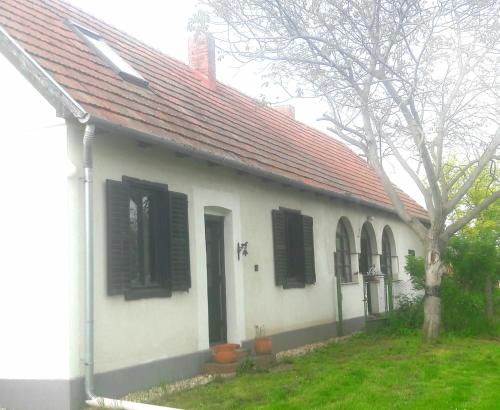 een wit huis met een rood dak en zwarte luiken bij VÁRBALOG in Várbalog