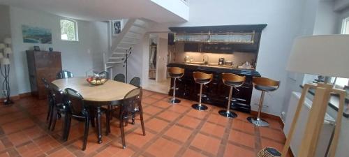 a kitchen with a table and a bar with stools at Le Mas de la Rocherie Chambre d'hôtes "Référence" in Pihen-lès-Guînes
