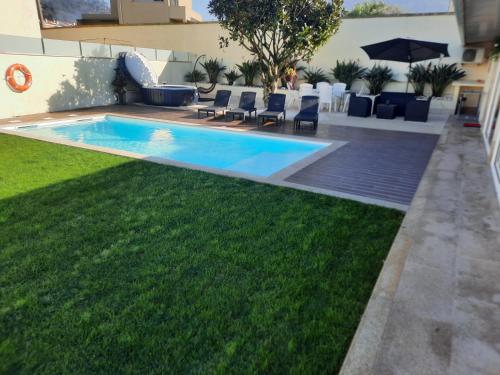 un patio trasero con piscina y césped verde en Michel's house en Esposende