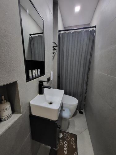 a bathroom with a sink and a toilet and a mirror at Luxury 3BR Villa w Plunge Pool near SM Batangas City- Instagram-Worthy! in Batangas City