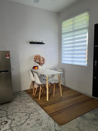 a white table and chairs in a kitchen with a window at Rumah Changgong in Kota Bharu