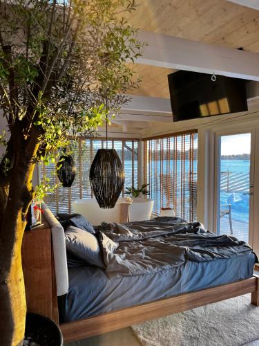 Un dormitorio con una cama grande y un árbol en Nordicstay Noarootsi Kastehein or Loojangu villa en Paslepa