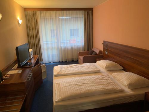 a hotel room with two beds and a desk with a television at Wellness & Spa Apartments Lipno - Frymburk in Frymburk