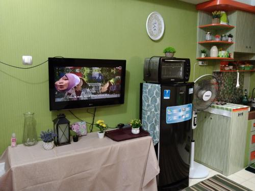 a room with a table and a tv on a wall at Green lake view Ciputat in Pondokcabe Hilir