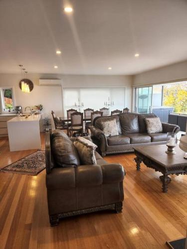 a living room with leather couches and a table at Luxury and Spacious Modern House, Spectacular View in Sandy Bay