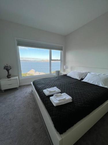 a bedroom with a large bed with two towels on it at Luxury and Spacious Modern House, Spectacular View in Sandy Bay