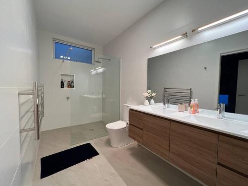 a bathroom with a sink and a toilet and a mirror at Luxury and Spacious Modern House, Spectacular View in Sandy Bay