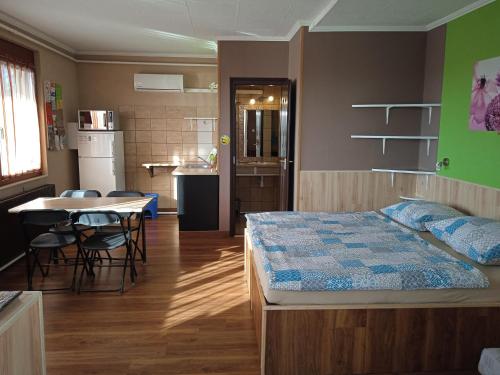 ein Schlafzimmer mit einem Bett und einem Tisch sowie eine Küche in der Unterkunft Málnás Szállás in Dunavarsány