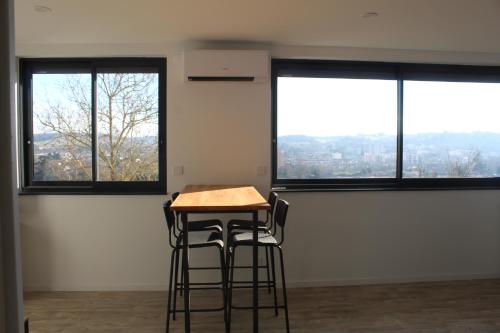 a table and two stools in an empty room with windows at Immeuble rénové au centre d'Auch. in Auch