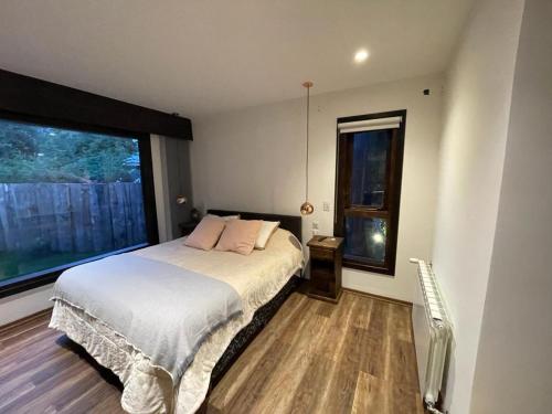 um quarto com uma cama e uma grande janela em CASA AZUL LIMAY VILLA LA ANGOSTURA em Villa La Angostura