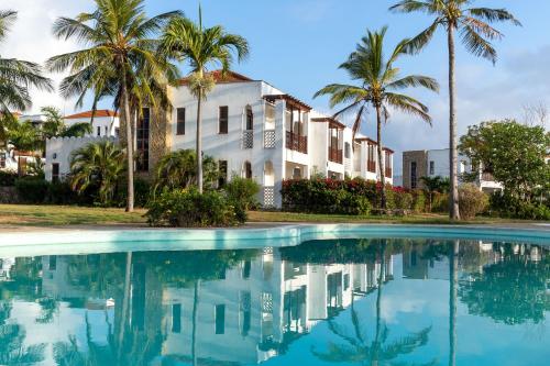 une maison avec des palmiers en face d'une piscine dans l'établissement Sultan Palace Beach Retreat Mombasa, à Mombasa