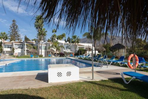 a swimming pool with chairs and a resort at Azahara 1 2B in Marbella