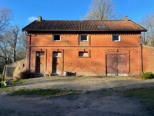 an old red brick building with two doors on it at La Bruyere du Coq Stables in Sart-Dames-Avelines