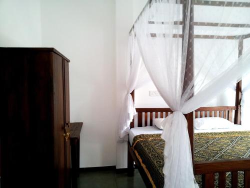 a bedroom with two beds with a canopy at Ceylon Surf Guest and Restaurant in Weligama