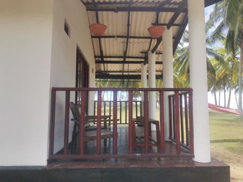 a porch of a house with two chairs on it at Helios Beach Resort in Tangalle