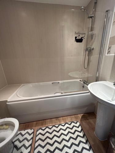 a bathroom with a tub and a toilet and a sink at Mannys Apartment - Nice & Cozy 4Bed Flagship Lodge in Sittingbourne