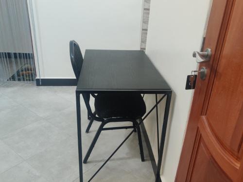 a black table with a black chair next to a door at FAD Home & Apartments in Dodoma