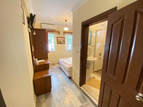a bathroom with a toilet and a bed and a door at Sevin Hotel Pension in Bodrum City