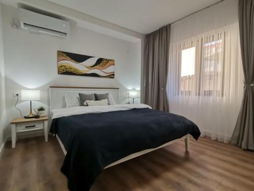 a white bedroom with a large bed and a window at Reggia Bitola in Bitola