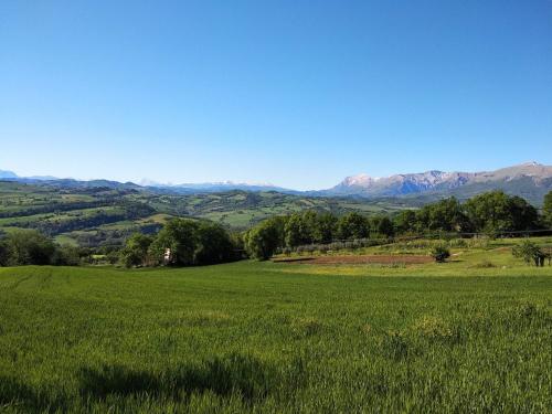 fuga sui sibillini في Gualdo di Macerata: حقل من العشب الأخضر مع الجبال في الخلفية
