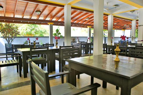 un ristorante con tavoli e sedie in legno, tavoli e panche di Esprit Bentota a Bentota